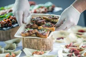 chef voorbereidingen treffen rauw rundvlees tandsteen mini brood Aan een catering evenement foto