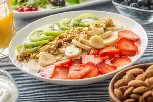 gezond ontbijt geserveerd met bord van yoghurt muesli kiwi aardbeien en banaan foto