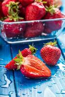 vers rijp aardbeien gewassen met water Aan blauw tafel foto
