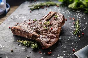 rundvlees t-bone steak met zout peper en rozemarijn Aan leisteen bord foto