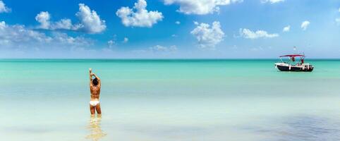 banier van een vrouw staand in warm turkoois schoon zee in tropisch paradijs genieten van vakantie met een boot Aan de kant foto