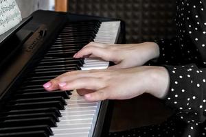 handen van een jonge meisjespianist op de toetsen van een synthesizer