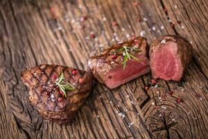 gegrild rundvlees steak met rozemarijn, zout en peper Aan oud snijdend bord. rundvlees lende steak. foto