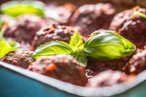 heerlijk Italiaans maaltijd vlees rundvlees ballen met basilicum in wijnoogst brander pan. foto