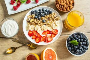 gezond ontbijt geserveerd met bord van yoghurt muesli bosbessen aardbeien en banaan. foto