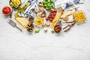 Italiaans voedsel ingrediënten pasta olijf- olie Parmezaanse kaas kaas basilicum knoflook champignons tomaten olijven Aan marmeren bord foto