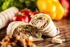 kebab gevulde tortilla wraps Aan een tafel met groenten in teh achtergrond foto