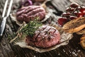 rauw hamburgers Aan houten tafel met ui tomaten kruiden en specerijen foto