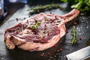 rauw rundvlees tomahawk steak met zout peper en rozemarijn Aan leisteen bord foto