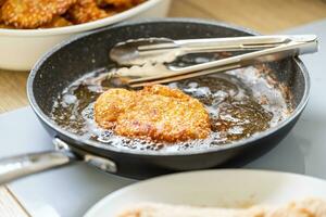 pan vol van olie is gebruikt voor frituren gepaneerd vlees terwijl maken worstje schnitzels foto