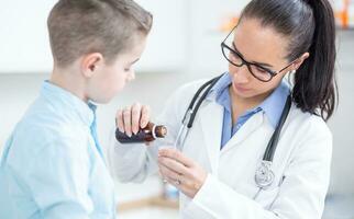 kinderarts vrouw dokter geven dosis van hoesten siroop naar jong een jongen geduldig foto