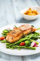 geroosterd Zalm steak met asperges broccoli wortel tomaten radijs groen bonen en erwten. vis maaltijd met vers groente foto