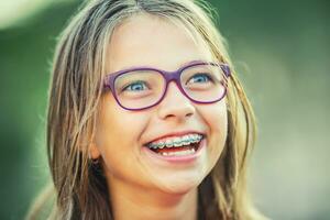gelukkig glimlachen meisje met tandheelkundig een beugel en bril. jong schattig Kaukasisch blond meisje vervelend tanden een beugel en bril foto