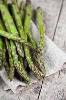 stelletje verse rauwe tuin asperges close-up en linnen servet op rustieke houten tafel achtergrond foto