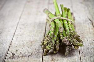 stelletje verse rauwe tuin asperges op rustieke houten tafel achtergrond. groene lentegroenten. foto