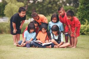 groep van kinderen aan het liegen lezing Aan gras veld- foto