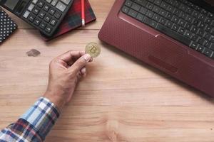 hand met gouden bitcoins op bureau foto