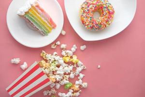 cake, donuts en popcorn op roze achtergrond foto