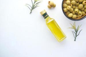 fles olijfolie en verse olijfolie in een container op tafel foto