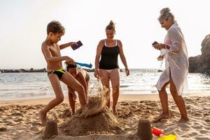 familie Aan vakantie spelen met zand kastelen Aan de strand Bij zonsondergang foto