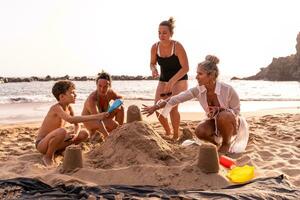 familie Aan vakantie spelen met zand kastelen Aan de strand Bij zonsondergang foto