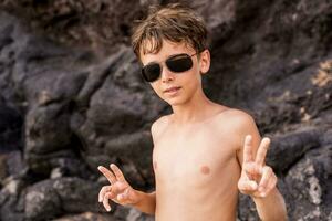 grappig portret van jong zonder shirt Mens vervelend zonnebril in een exotisch strand foto