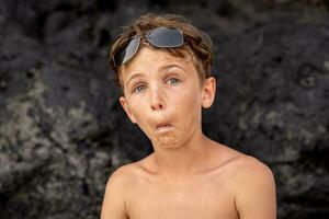 grappig portret van jong zonder shirt Mens vervelend zonnebril in een exotisch strand foto