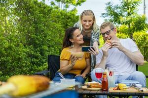 familie van moeder en haar kinderen nemen selfie Bij bbq picknick vakantie Bij hun achtertuin gedurende zomer terwijl hebben mooi zo voedsel en tijd samen voor liefde en broer of zus concept foto