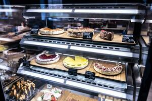 banketbakkerij vitrine van breed verscheidenheid van snoepgoed en desserts achter de gekoeld glas foto