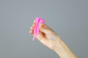 detailopname van een vrouw handen vouwen een menstruatie- kop tonen hoe naar gebruik het, vorm c. nul verspilling alternatief concept foto