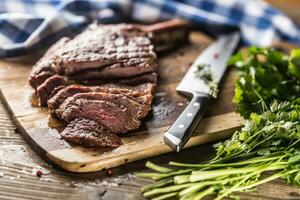 vers gegrild tomahawk steak Aan leisteen bord met zout peper rozemarijn en peterselie kruiden. gesneden stukken van sappig rundvlees steak foto