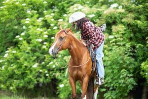 vrouw krijgen uit de paard met een voet nog steeds in de stijgbeugel foto