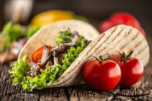 Open vlees en veg tortilla Aan een rustiek houten bord foto