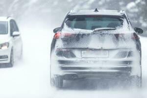 suv auto het rijden Aan besneeuwd glad weg binnen de Woud, hebben registratie aantal onzichtbaar ten gevolge naar sneeuw foto