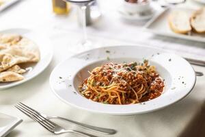 restaurant portie van spaghetti bolognese met geraspt kaas Aan top Aan een wit tafel foto