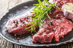 rundvlees meet biefstuk steak verstand rozemarijn zout en peper Aan zwart bord foto