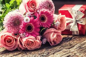 mooi boeket van bloemen met rood geschenk Aan houten tafel. foto