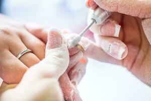 repareren oud gel nagels met een nagel Slijper in nagel studio - salon. nagels manicuren. foto