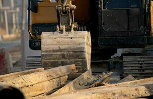 graver geparkeerd Bij bouw plaats met metaal bar. backhoe na werk. aarde in beweging machine. uitgraving voertuig. bouw plaats met graafmachine. infrastructuur ontwikkeling. bouw industrie. foto