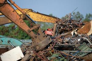 graafmachine magneet hijs- staal kladjes van recycling materialen stapel Bij vodje werf in recycling fabriek. graafmachine met elektro en magnetisch zuignap magneet klauw. speciaal graafmachine. vodje metaal magneet. foto