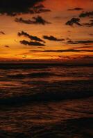 verbazingwekkend helder oranje zonsondergang Aan de Indisch oceaan met golven Aan Bali eiland. avond zonlicht, brand lucht foto