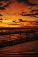 verbazingwekkend helder oranje zonsondergang Aan de Indisch oceaan met golven Aan Bali eiland. avond zonlicht, brand lucht foto