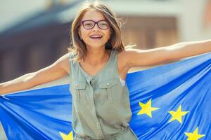 EU vlag. schattig gelukkig meisje met de vlag van de Europese unie. jong tiener- meisje golvend met de Europese unie vlag in de stad foto