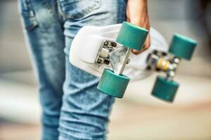 dichtbij omhoog van meisje of jongen Holding zijn cent skateboard foto