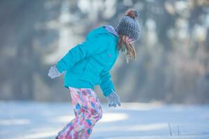 gelukkig jong pre-tiener meisje in warm kleding spelen met sneeuw foto