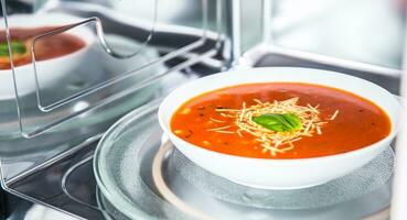 binnen visie van nieuw schoon staloos magnetronoven oven met een tomaat soep in wit bord foto