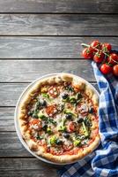 irtaal pizza met broccoli spinazie tomaten olijven en mozzarela of Parmezaanse kaas kaas. middellandse Zee vegetarisch maaltijd foto