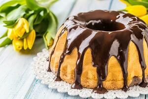 heerlijk vakantie Slowaaks en Tsjechisch taart babovka met chocola glazuur. Pasen decoraties - voorjaar tulpen en eieren foto