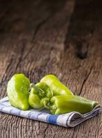 groen peper.fris groen peper blauw geruit tafelkleed Aan oud eik tafel. foto