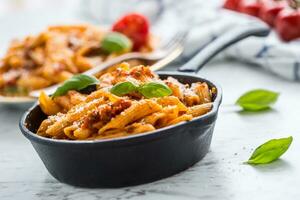 Italiaans voedsel en pasta penne met bolognese sausen in pan foto
